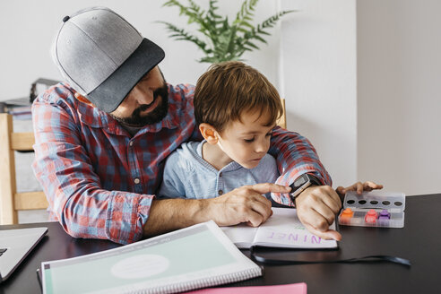 Vater erklärt seinem Sohn die Smartwatch, während er zu Hause arbeitet - JRFF01998