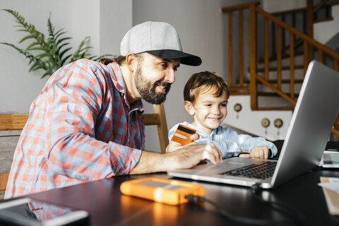 Vater und Sohn benutzen gemeinsam einen Laptop, Online-Shopping, lizenzfreies Stockfoto