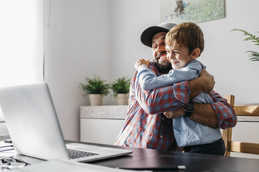 Father sitting at desk, embracing his son - JRFF02001