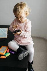 Little girl using mobile phone, sitting on desk - JRFF02006