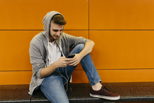 Junger Mann, der auf die U-Bahn wartet und sein Smartphone benutzt - JRFF02024