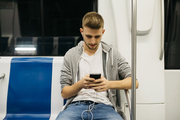 Junger Mann benutzt Smartphone in der U-Bahn - JRFF02026