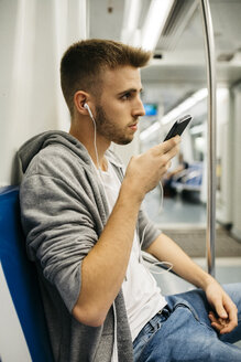 Junger Mann benutzt Smartphone in der U-Bahn - JRFF02027