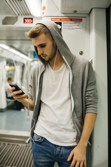 Junger Mann benutzt Smartphone in der U-Bahn - JRFF02029