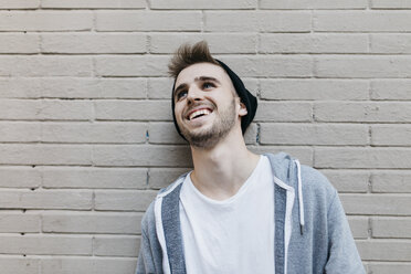 Young man laughing in front of wall, portrait - JRFF02033