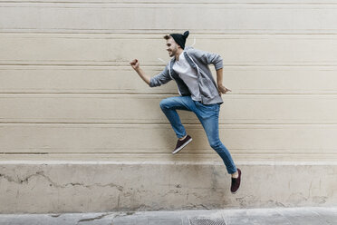 Glücklicher junger Mann, der vor eine Mauer springt - JRFF02035