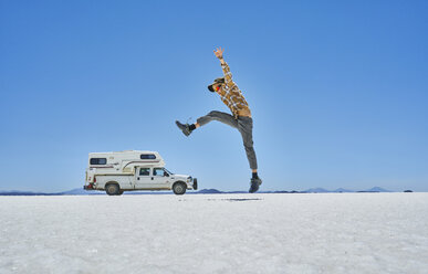 Bolivien, Salar de Uyuni, Junge springt auf Wohnmobil am Salzsee - SSCF00018