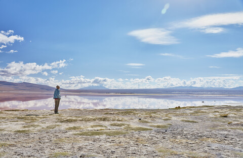 Bolivien, Laguna Colorada, Frau steht am Seeufer und schaut auf die Aussicht, lizenzfreies Stockfoto