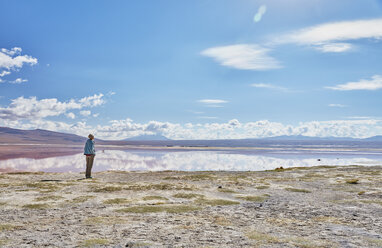 Bolivien, Laguna Colorada, Frau steht am Seeufer und schaut auf die Aussicht - SSCF00036
