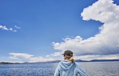 Bolivien, Titicacasee, Frau am Seeufer mit Blick auf die Aussicht, lizenzfreies Stockfoto