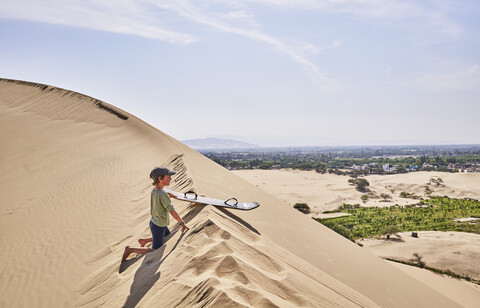 Peru, Ica, Junge mit Sandboard auf Sanddüne, lizenzfreies Stockfoto