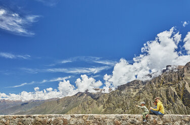 Peru, Chivay, Colca Canyon, woman sitting with sons on wall looking at canyon - SSCF00068