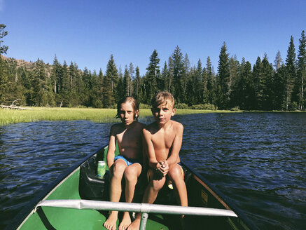 Hemdlose Brüder sitzen in einem Boot auf dem Rucker See während eines sonnigen Tages im Wald - CAVF55880