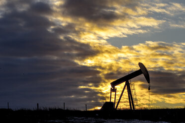 Pumpjack in der Ölindustrie vor bewölktem Himmel bei Sonnenuntergang - CAVF55958