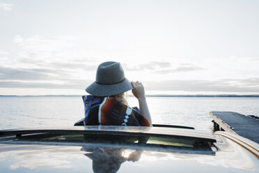 Woman wearing hat looking at view through sun roof against sky - CAVF55975