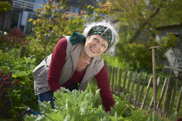 Porträt einer fröhlichen älteren Frau bei der Gartenarbeit im Hinterhof - CAVF55982
