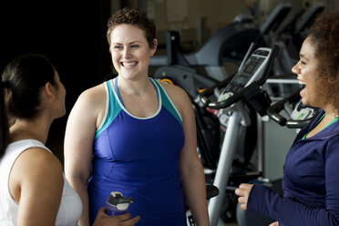 Female friends talking while standing in gym - CAVF56001