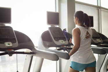 Rear view of woman on treadmill in gym - CAVF56003