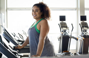 Porträt einer kurvigen Frau auf dem Laufband im Fitnessstudio - CAVF56005