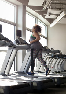 Full length of curvy woman running on treadmill in gym stock photo