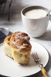 Selbstgebackene Zimtschnecke mit Puderzucker und eine Tasse Kaffee - SBDF03844