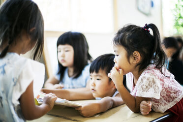 Eine Gruppe von Kindern sitzt an einem Tisch in einer japanischen Vorschule. - MINF09630