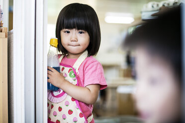 Mädchen mit rosa-weißer Schürze steht in einer japanischen Vorschule in der Tür. - MINF09633