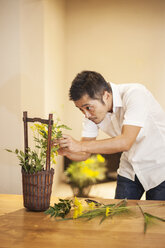 Japaner in einer Blumengalerie, der an einem Ikebana-Arrangement arbeitet. - MINF09641