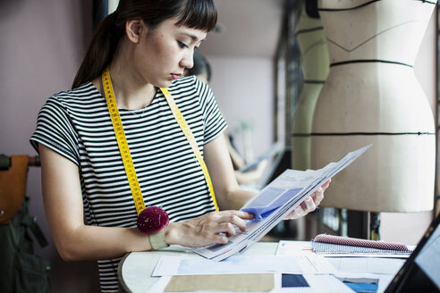 Japanische Modedesignerin bei der Arbeit in ihrem Atelier, die sich Stoffmuster ansieht. - MINF09657