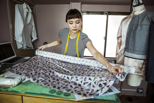 Japanische Modedesignerin bei der Arbeit in ihrem Atelier, beim Messen von Stoffen. - MINF09663