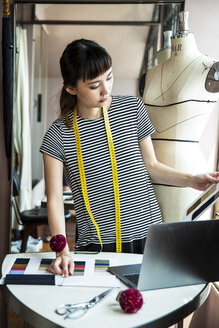 Eine japanische Modedesignerin steht am Schreibtisch und arbeitet in ihrem Atelier. - MINF09665