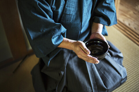 Nahaufnahme eines japanischen Mannes im Kimono, der eine Teeschale während einer Teezeremonie hält., lizenzfreies Stockfoto