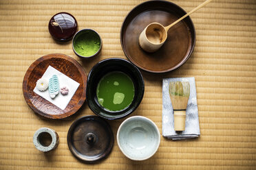 Utensilien für die Teezeremonie, darunter eine Schale mit grünem Matcha-Tee, ein Bambusbesen und Wagashi-Bonbons. - MINF09695