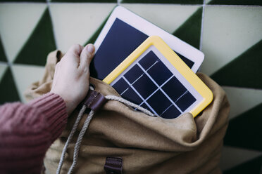 Frau packt ein Tablet in einen Rucksack mit einem Solarpanel-Ladegerät - GEMF02565