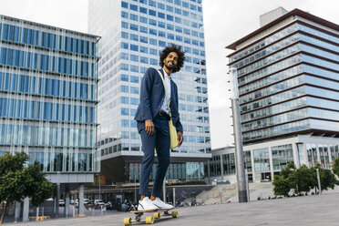 Spanien, Barcelona, junger Geschäftsmann fährt Skateboard in der Stadt - JRFF02038