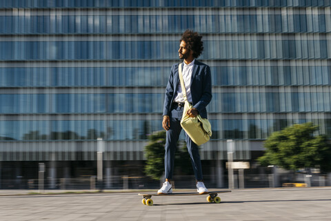 Spanien, Barcelona, junger Geschäftsmann fährt Skateboard in der Stadt, lizenzfreies Stockfoto