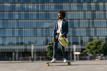 Spanien, Barcelona, junger Geschäftsmann fährt Skateboard in der Stadt - JRFF02042