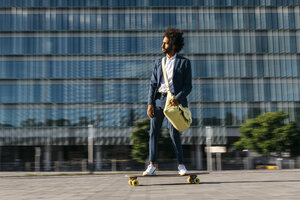 Spanien, Barcelona, junger Geschäftsmann fährt Skateboard in der Stadt - JRFF02042