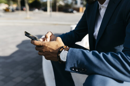 Nahaufnahme eines im Freien sitzenden Geschäftsmannes, der ein Mobiltelefon benutzt - JRFF02043