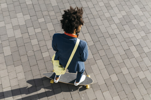 Junger Geschäftsmann fährt Skateboard auf einem Platz, lizenzfreies Stockfoto