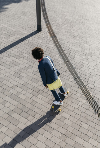 Junger Geschäftsmann fährt Skateboard auf einem Platz, lizenzfreies Stockfoto