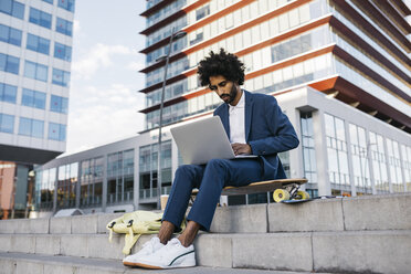 Spain, Barcelona, young businessman sitting outdoors in the city working on laptop - JRFF02064