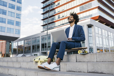 Spanien, Barcelona, junger Geschäftsmann sitzt in der Stadt im Freien und arbeitet am Laptop - JRFF02065