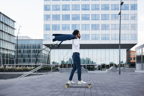 Spanien, Barcelona, junger Geschäftsmann fährt Skateboard in der Stadt - JRFF02076