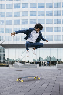 Spanien, Barcelona, junger Geschäftsmann macht Skateboardtricks in der Stadt - JRFF02078