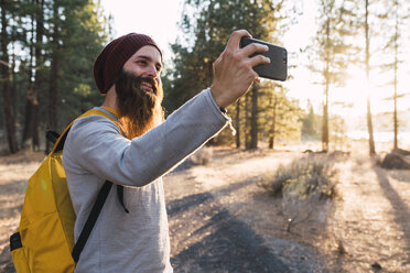 USA, Nordkalifornien, lächelnder bärtiger Mann, der ein Selfie in einem Wald in der Nähe des Lassen Volcanic National Park macht - KKAF02978