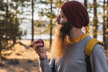 USA, North California, bearded man eating an apple in a forest near Lassen Volcanic National Park - KKAF02979
