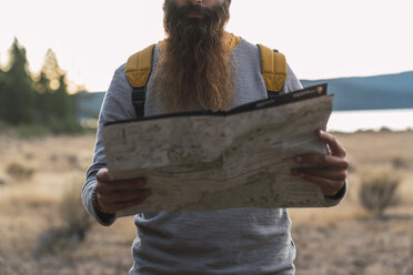 USA, North California, close-up of bearded man reading map on a hiking trip near Lassen Volcanic National Park - KKAF02988