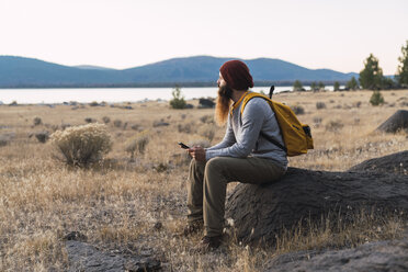 USA, Nordkalifornien, bärtiger junger Mann, der auf einer Wanderung in der Nähe des Lassen Volcanic National Park eine Pause einlegt - KKAF02989