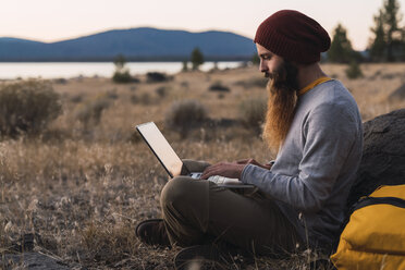 USA, Nordkalifornien, bärtiger junger Mann mit Laptop in der Nähe des Lassen Volcanic National Park - KKAF02992